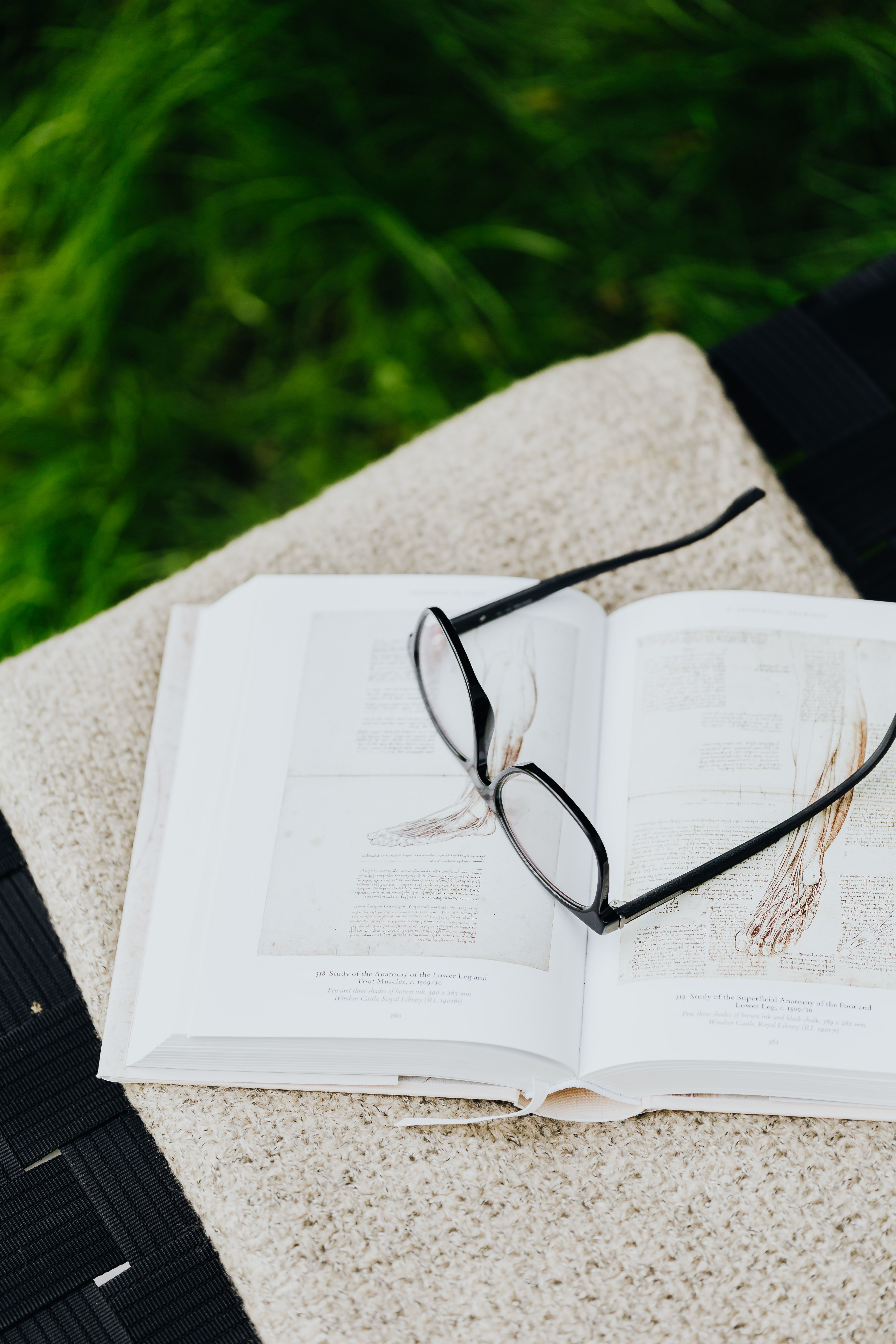 Reading glasses resting on an open research book about reflexology